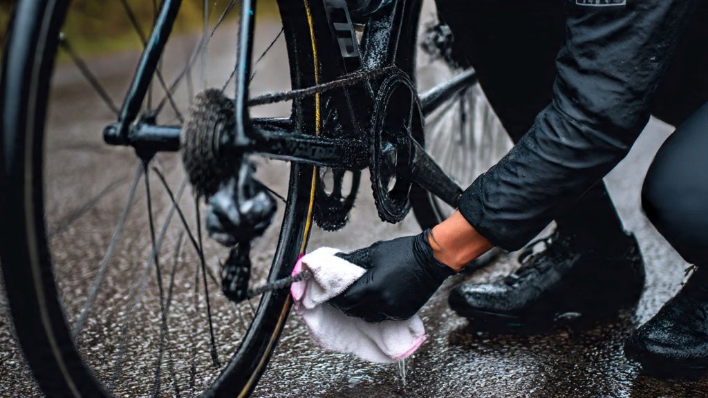1. Cyclist cleaning bike bottom bracket area with cloth after riding in rain