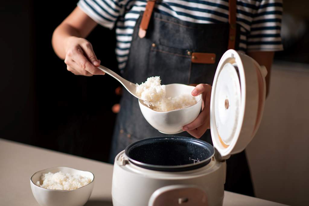 Person using Aroma digital rice cooker controls for easy meal prep